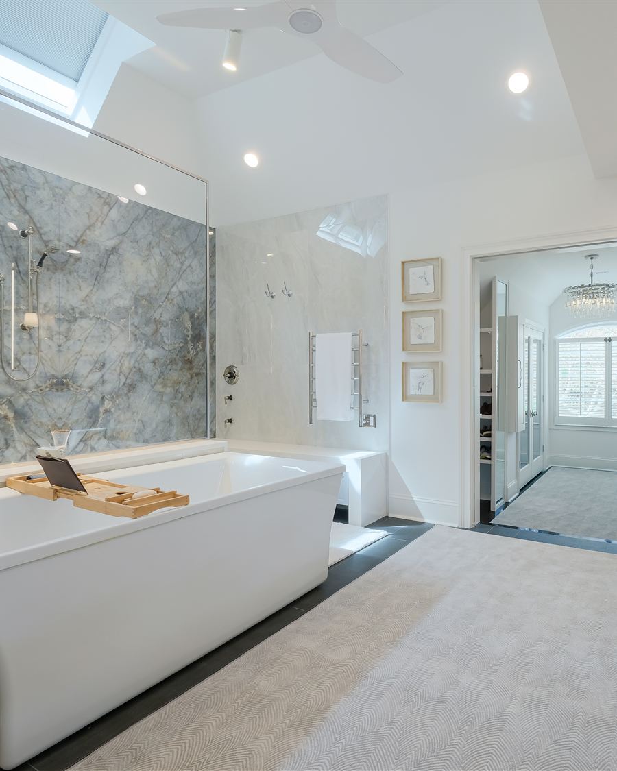 The same bathroom after renovation: book-matched porcelain slab shower, freestanding soaking tub and custom inset vanities