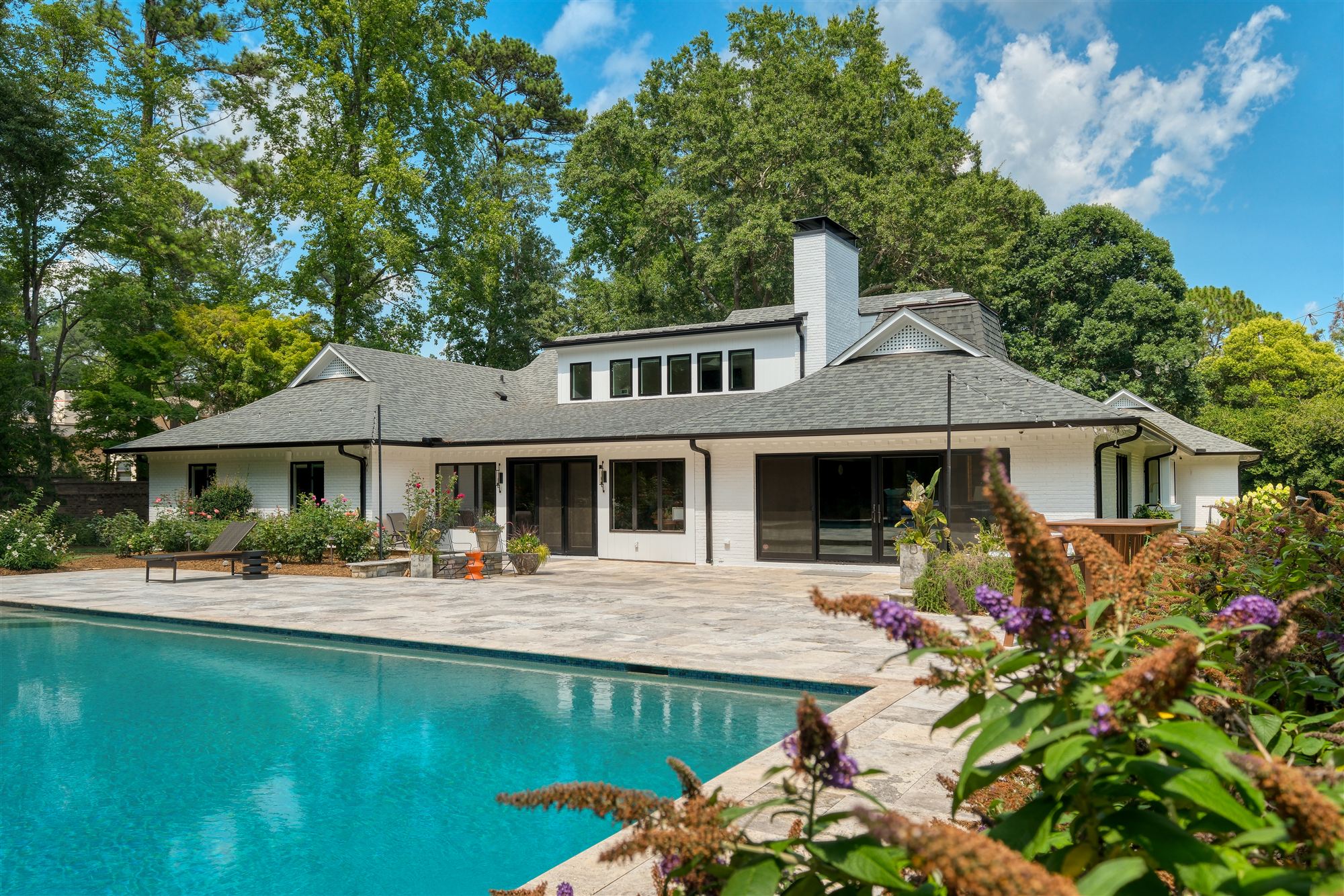 White-brick ranch exterior with resort-style pool and landscaped patio, Pellyn Wood whole-home renovation in SouthPark, Charlotte
