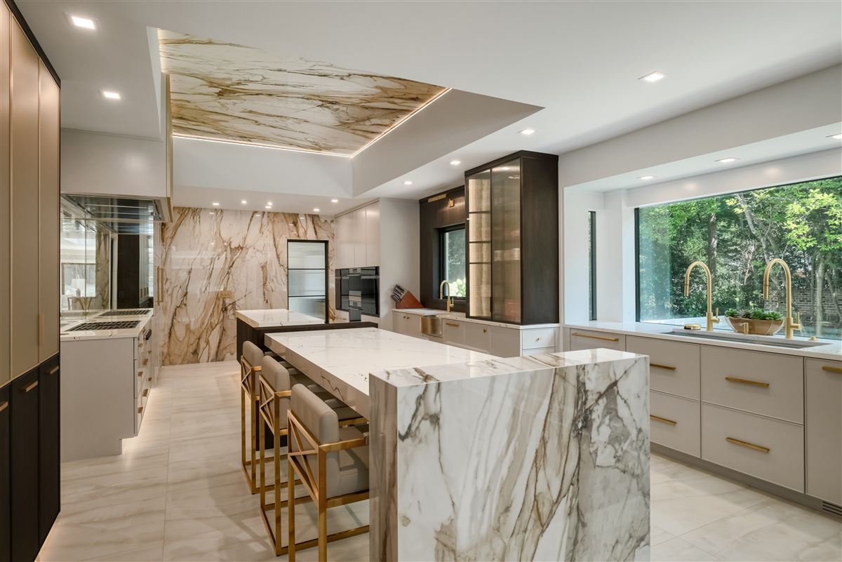 Custom kitchen with gold-veined porcelain slab island and reeded brass-framed glass cabinets, Pellyn Wood renovation, SouthPark, Charlotte