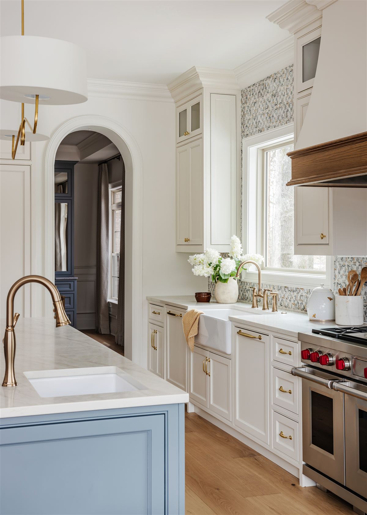 Cream chef's kitchen with custom wood hood, arched doorway and brass fixtures, Waxhaw whole-home renovation